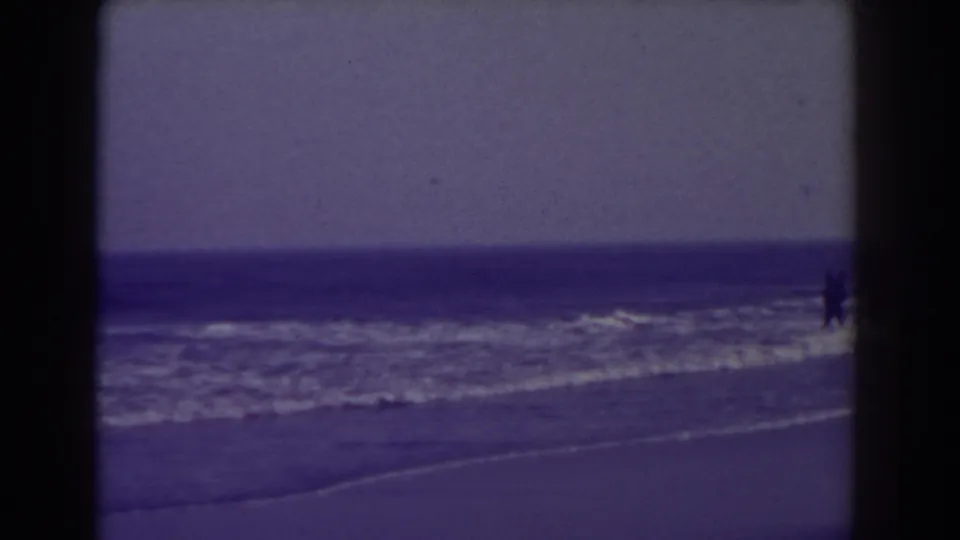 Atlantic City shoreline frame from 1938 showing low waves, open water, broad sand, and distant figures at the edge of the surf.