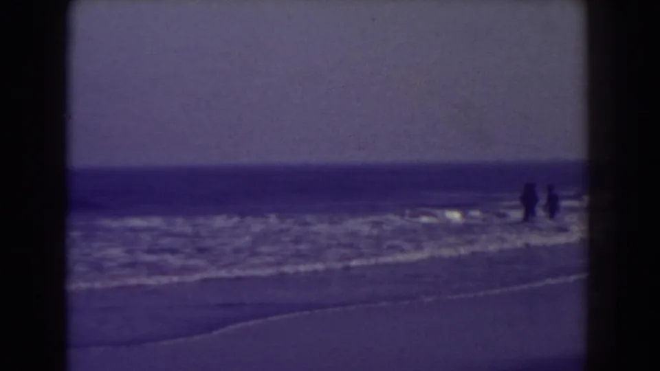 1938 Atlantic City beach view with distant figures near the waterline under a muted sky.