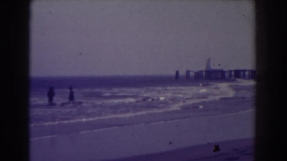Atlantic City shoreline scene from 1938 with distant walkers and a pier extending over the water.