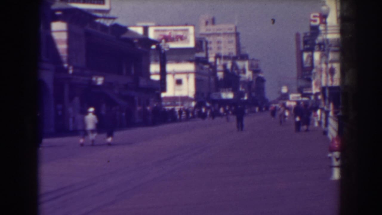 Atlantic City street with pedestrians, storefronts, signs, and distant buildings.