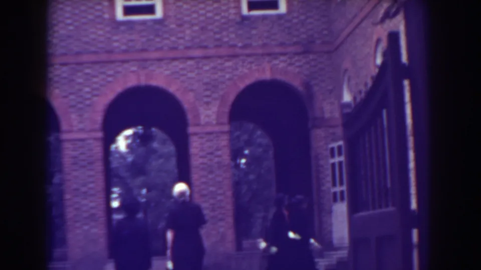1938 Atlantic City frame showing pedestrians under brick arches near steps, trees, and a large open gate.