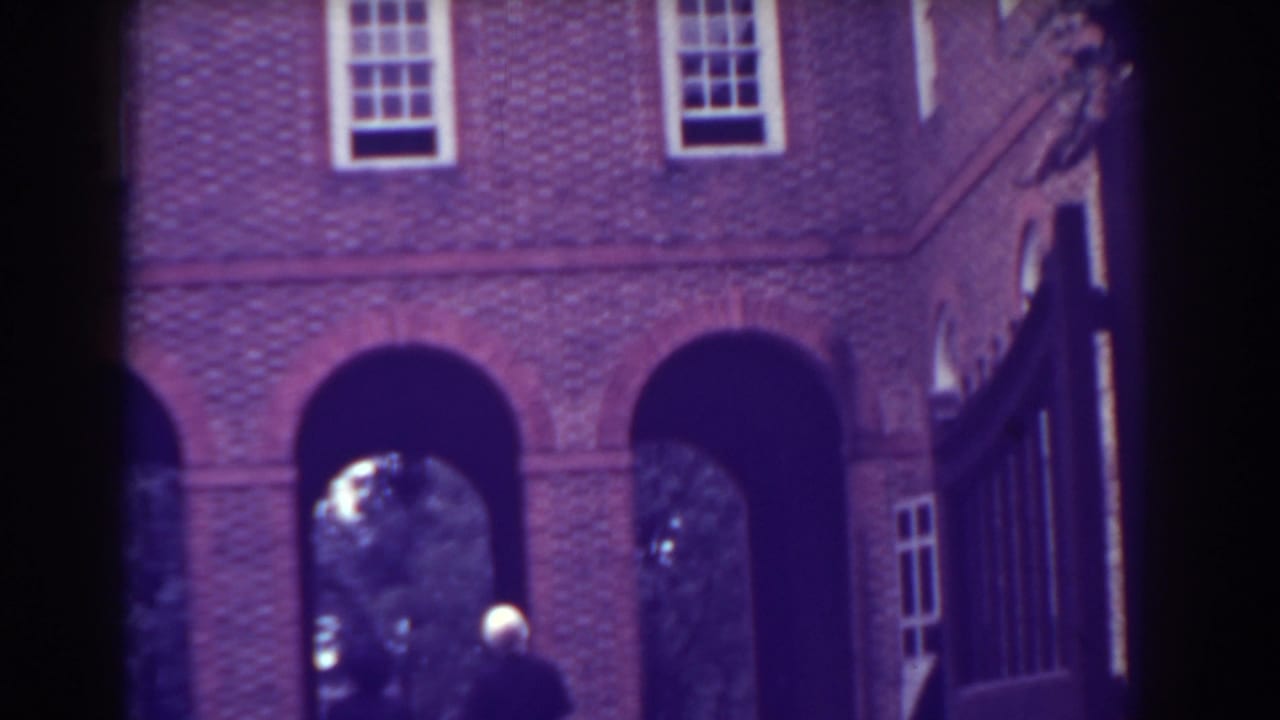 Brick building with arched openings and a distant person near the entrance.