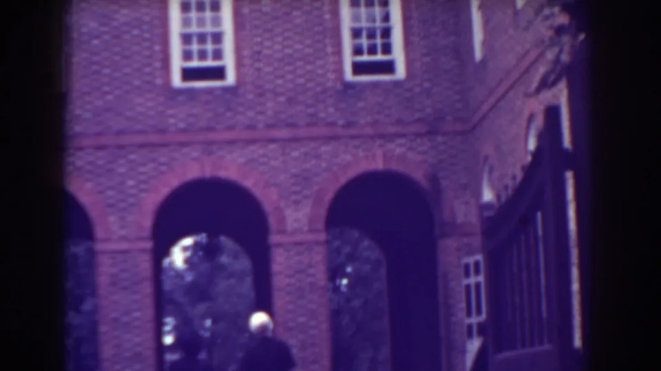 1938 Atlantic City 8mm frame showing a brick manor-like exterior with arched openings and a distant person near the entrance.