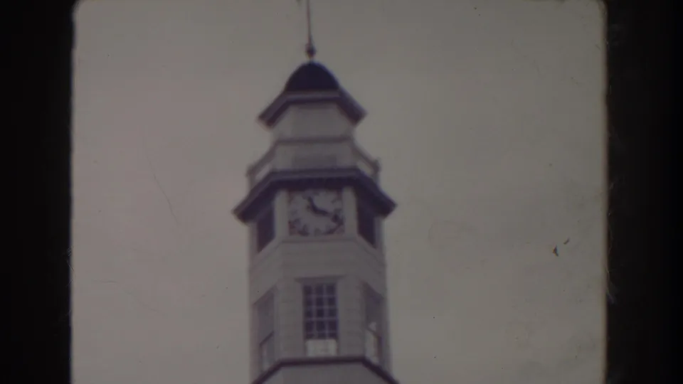1938 Atlantic City 8mm frame showing a clock tower topped by a flag, with soft focus and dark film edges.