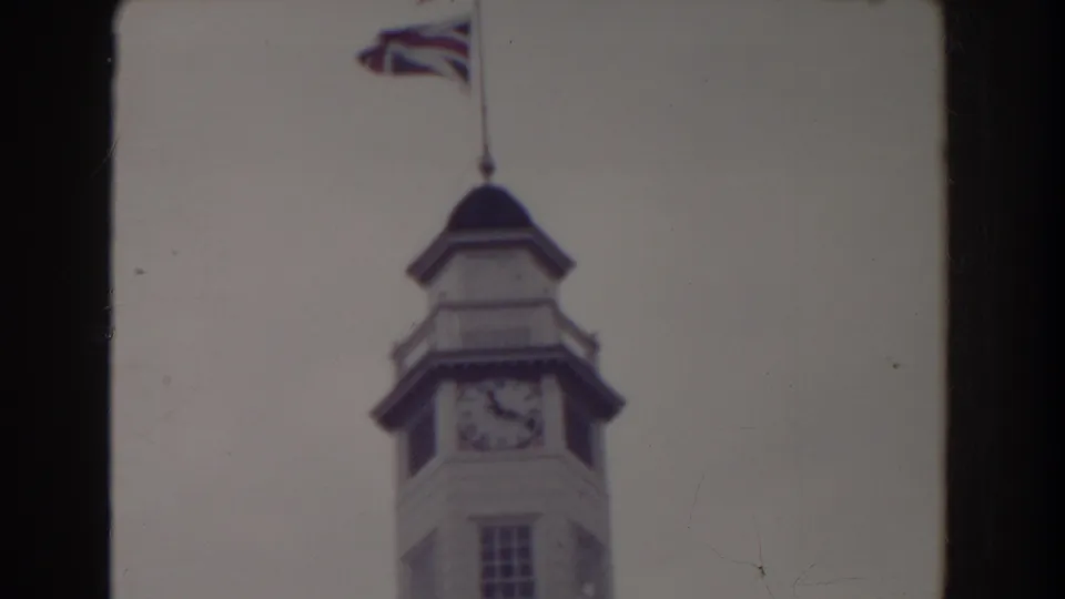 1938 Atlantic City view of a clock tower and flag, cropped by the 8mm frame edge and softened by the film scan.
