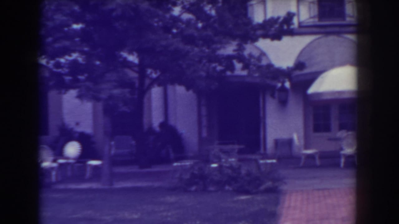 Atlantic City patio view in 1938 with outdoor chairs, small tables, trees, and a large building entrance in soft 8mm color.