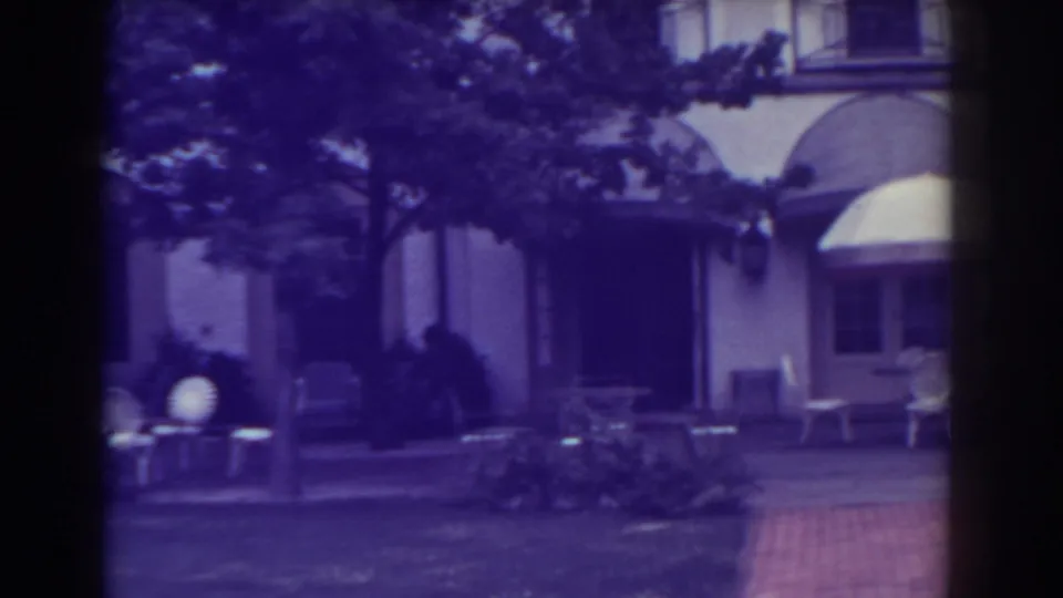 Atlantic City patio view in 1938 with outdoor chairs, small tables, trees, and a large building entrance in soft 8mm color.