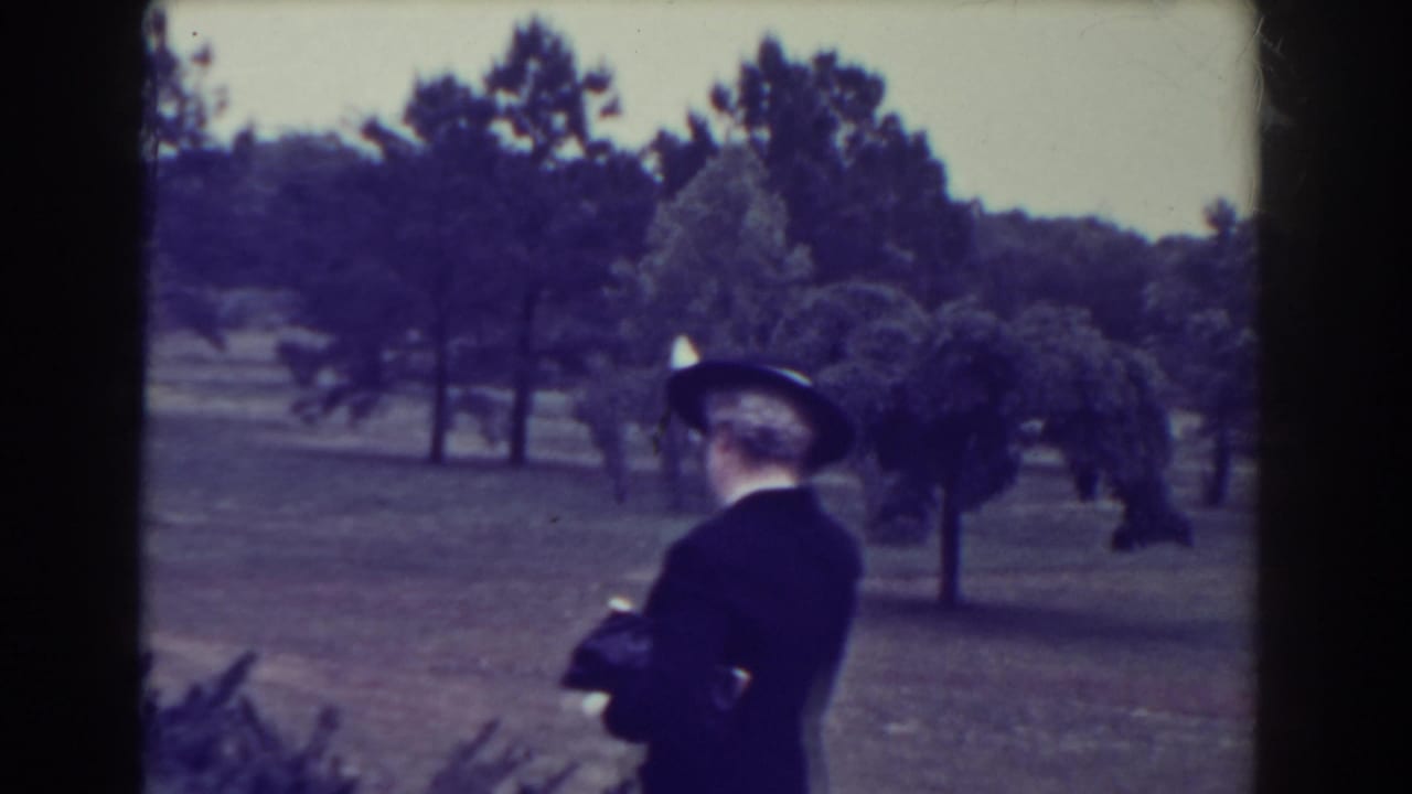The woman turns away from the camera on a landscaped Atlantic City park path, with trees and open lawn in the background.