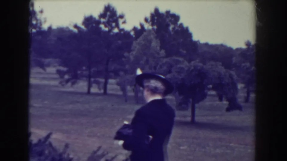 The woman turns away from the camera on a landscaped Atlantic City park path, with trees and open lawn in the background.