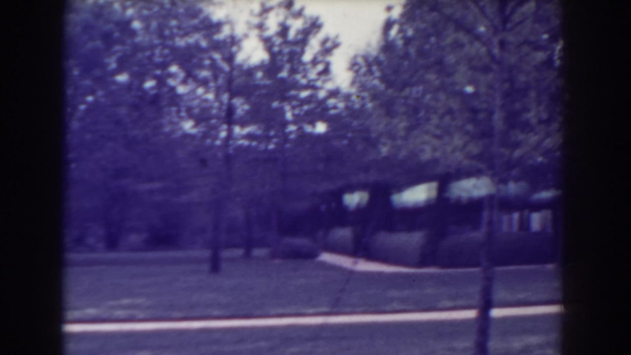 Atlantic City home-movie frame from 1938 with trees, grass, path, and a partial house exterior in the background.