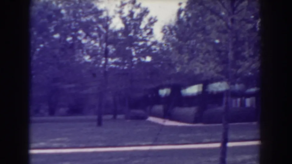Atlantic City home-movie frame from 1938 with trees, grass, path, and a partial house exterior in the background.