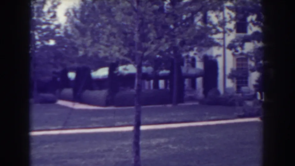 1938 Atlantic City frame showing a landscaped lawn, trees, shrubs, and a house facade beyond the path.