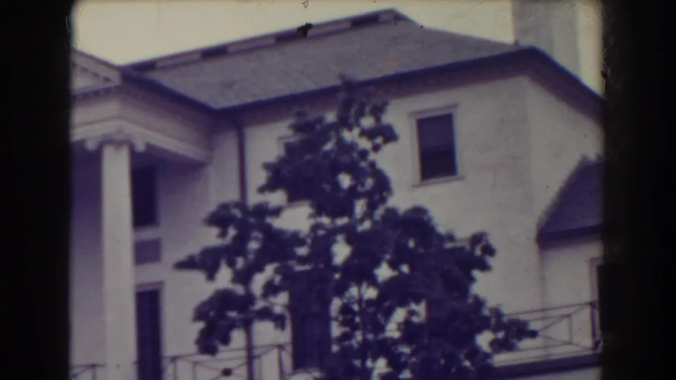1938 Atlantic City view of the upper facade, showing columns, slate-colored roof sections, balcony railing, and foreground tree branches.