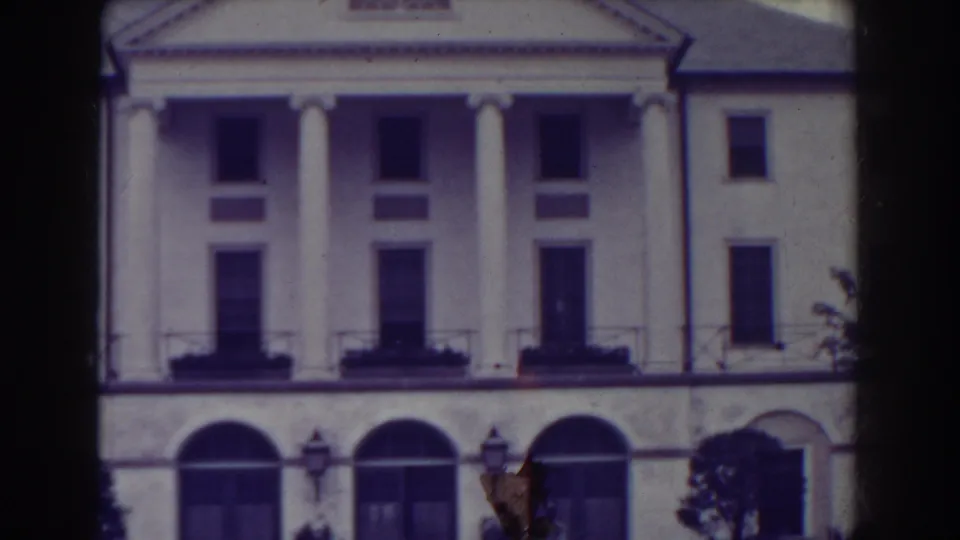1938 Atlantic City home-movie view of a symmetrical white facade with columns above arched lower openings, balcony railings and window boxes.