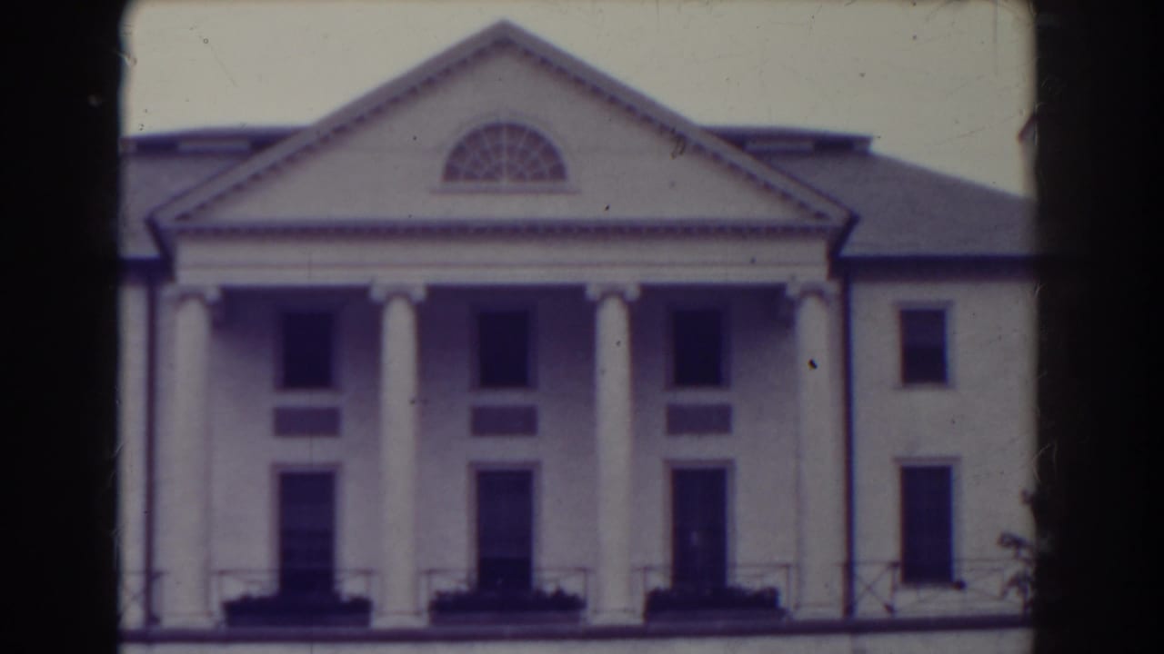 White classical building facade with columns and triangular pediment.