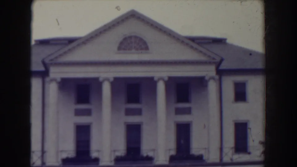 1938 Atlantic City frame holding on the white columned building, with soft focus, dark window openings, and visible 8mm frame edges.