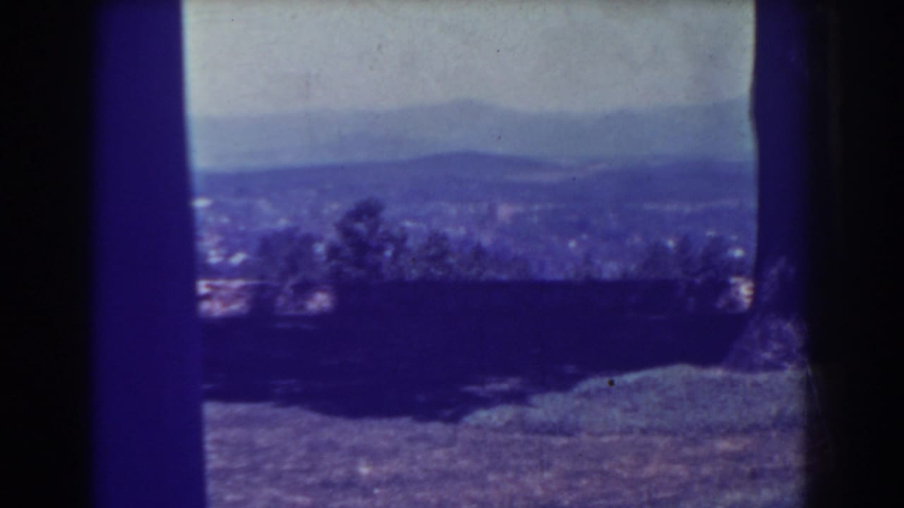 Distant valley and hills seen through dark 8mm film edges with trees in the foreground.