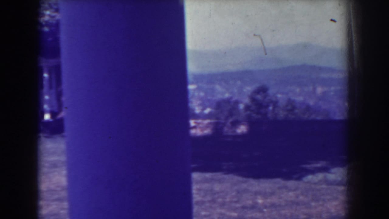 Distant hills and valley landscape framed by dark vertical film borders.