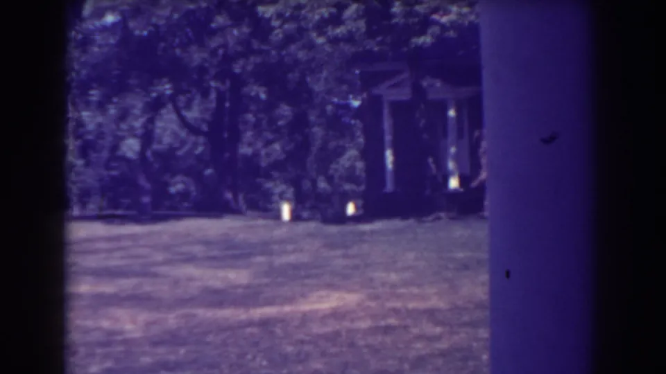 1938 Atlantic City home-movie frame showing a shaded grassy overlook with trees and a partial structure at the edge of the view.