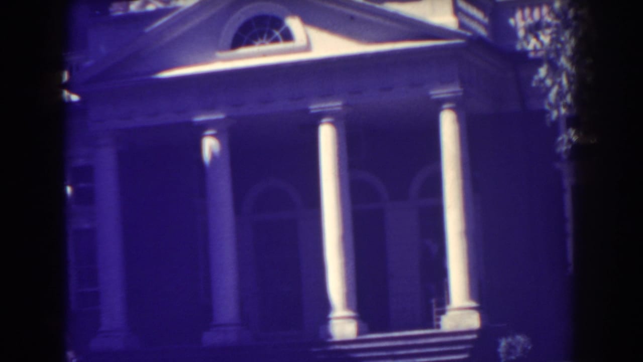 White-columned building entrance with arched windows and pediment, tinted purple by aged film.
