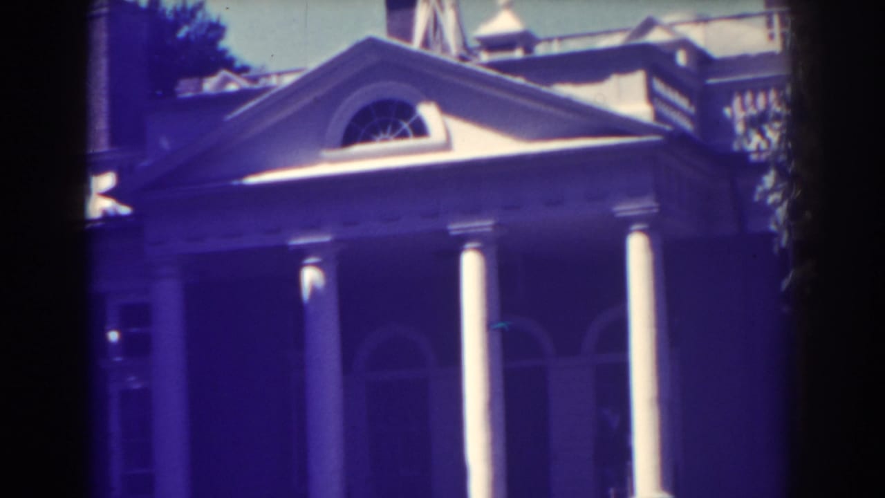 1938 Atlantic City frame of a classical portico, with bright white columns, an arched entrance, and heavy blue-purple film tint.