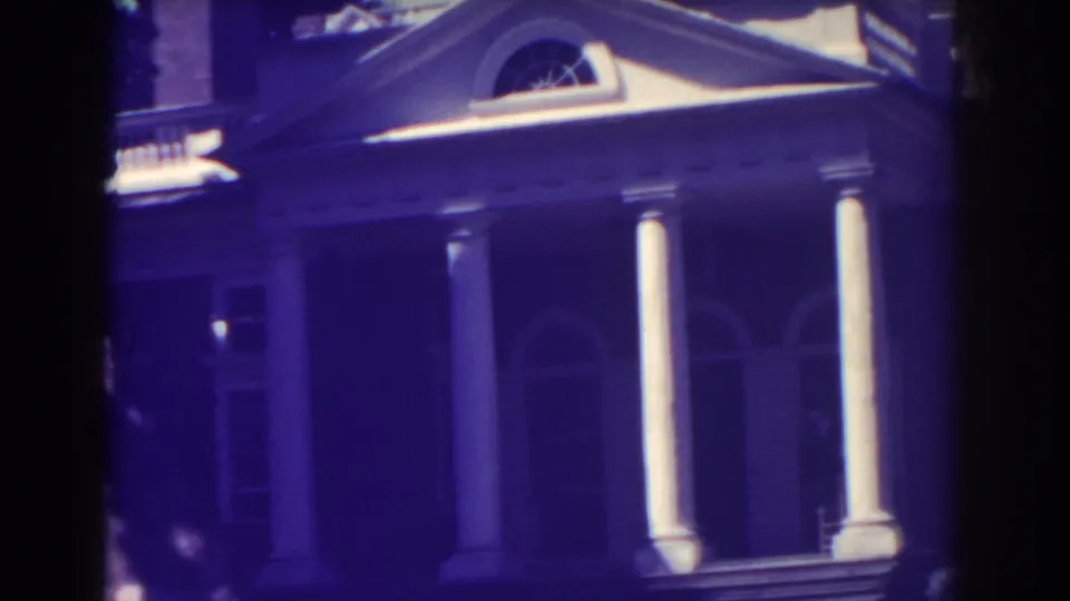 1938 Atlantic City home-movie still showing the lower portion of a white-columned entrance, arched windows, steps, and dark aged-film shadows.