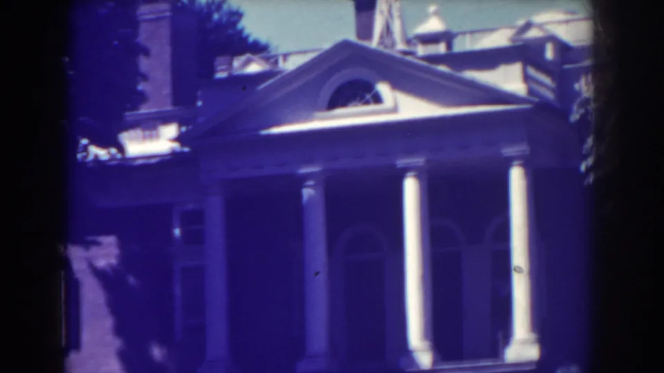 Late frame from the 1938 Atlantic City clip showing the pediment, white columns, brick facade, and nearby rooftop edges.