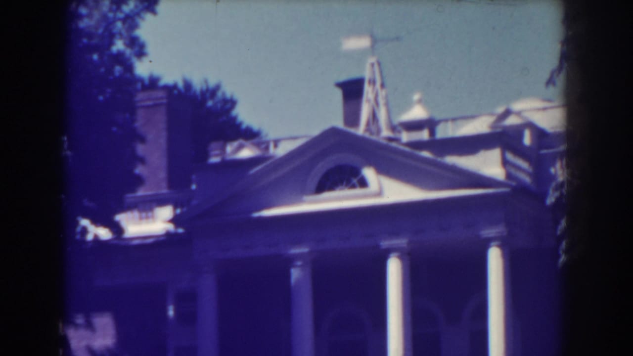 1938 Atlantic City frame of a stately house exterior, showing white porch columns, roof elements, an arched window, and surrounding trees.