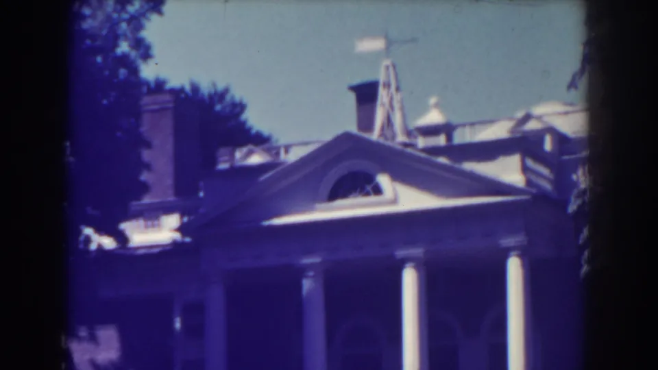 1938 Atlantic City frame of a stately house exterior, showing white porch columns, roof elements, an arched window, and surrounding trees.