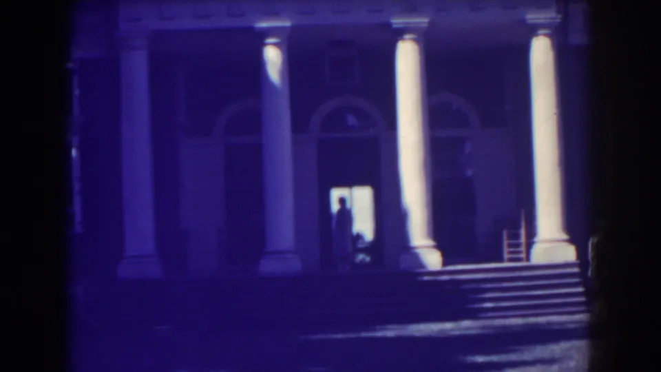 1938 Atlantic City home-movie view of the mansion entrance, with broad steps, tall columns, arched doors, and a person silhouetted inside the doorway.