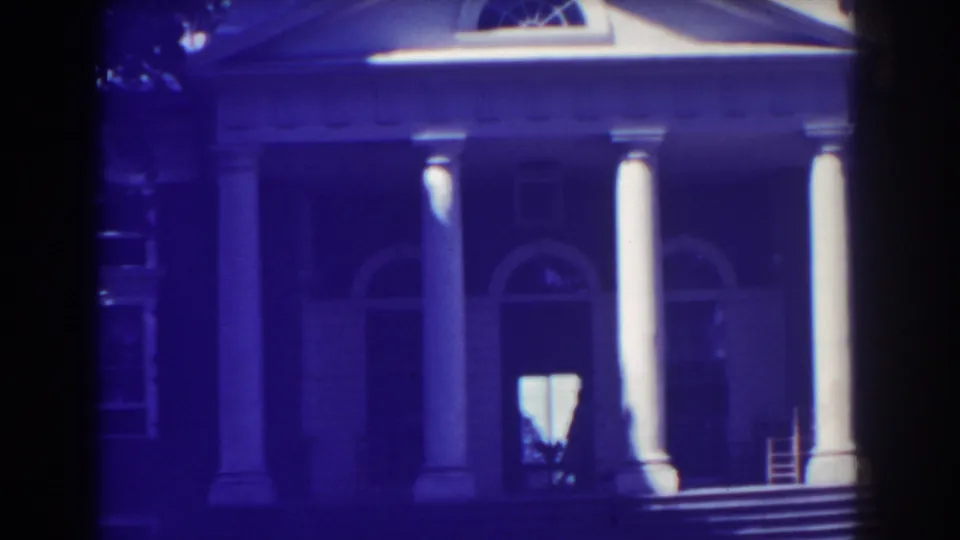 1938 Atlantic City frame emphasizing the building's white columns, arched windows, steps, and bright entrance with a dark figure near the doorway.