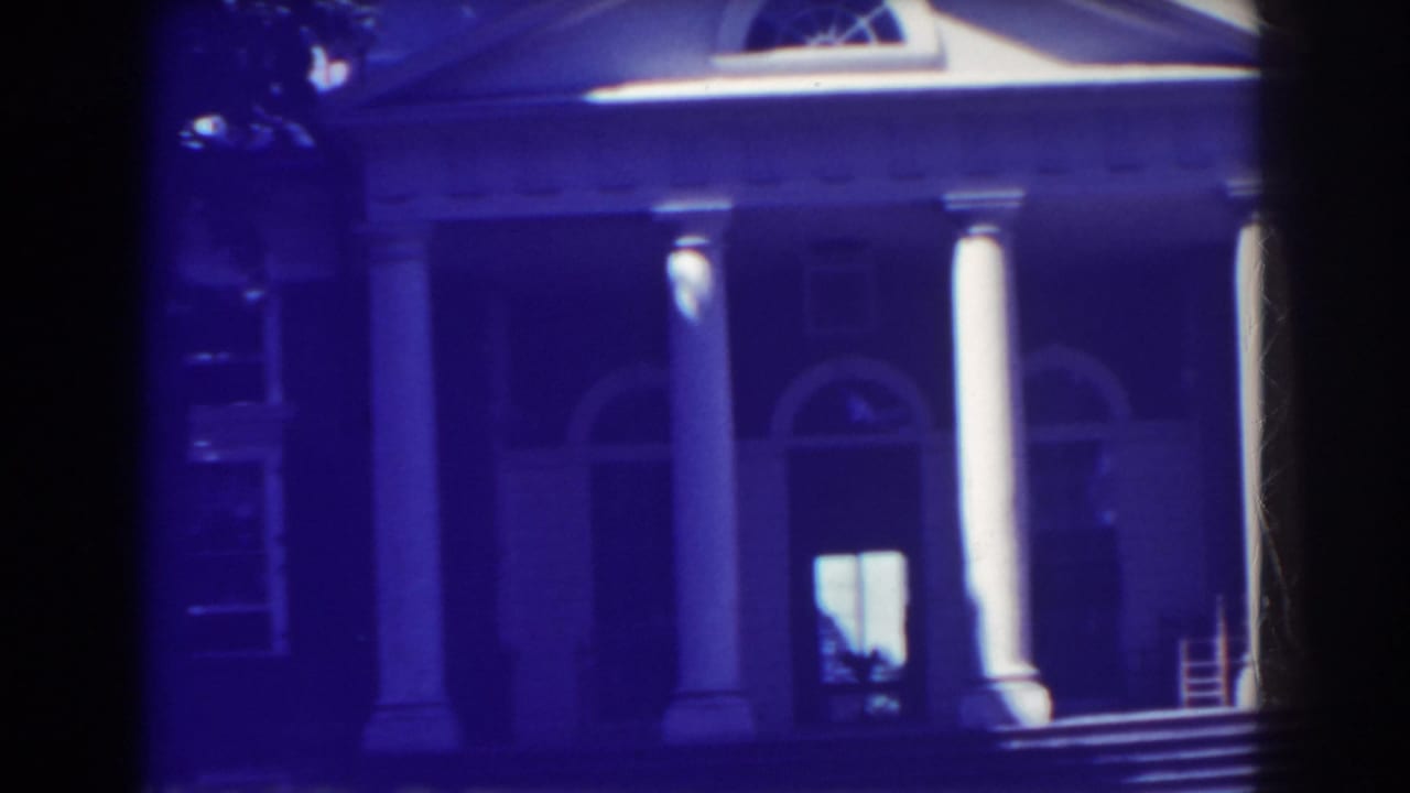 Columned building facade with arched windows and porch steps in soft blue-tinted film.