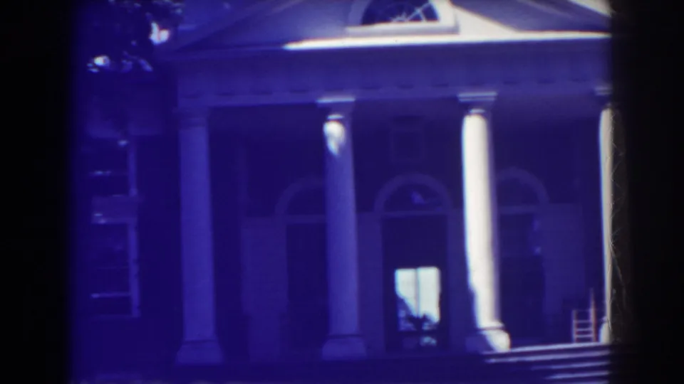 1938 Atlantic City home-movie frame showing a stately facade with white columns, arched openings, porch steps, and dark tree shade.
