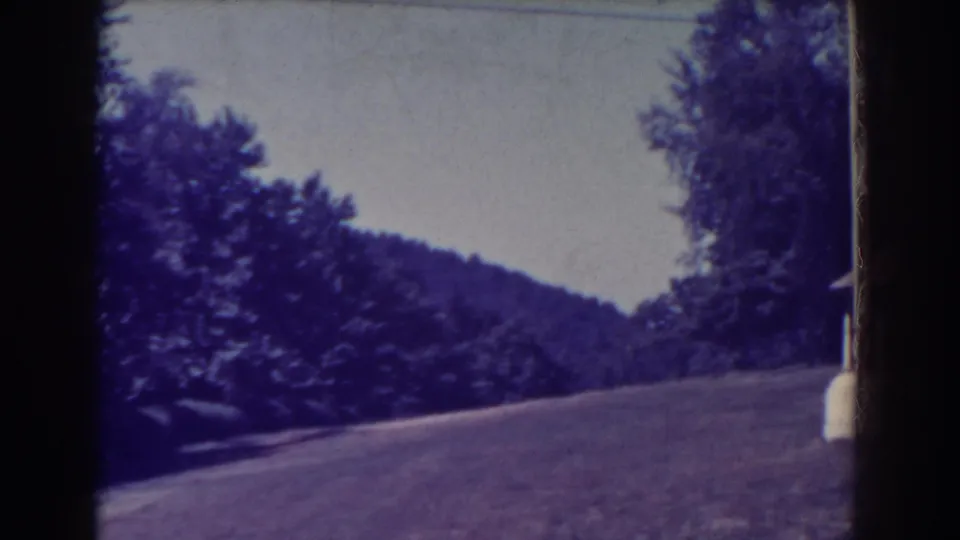 1938 Atlantic City frame showing the hillside grounds after the pan, with lawn, trees, wooded hill, and a partial white pole.