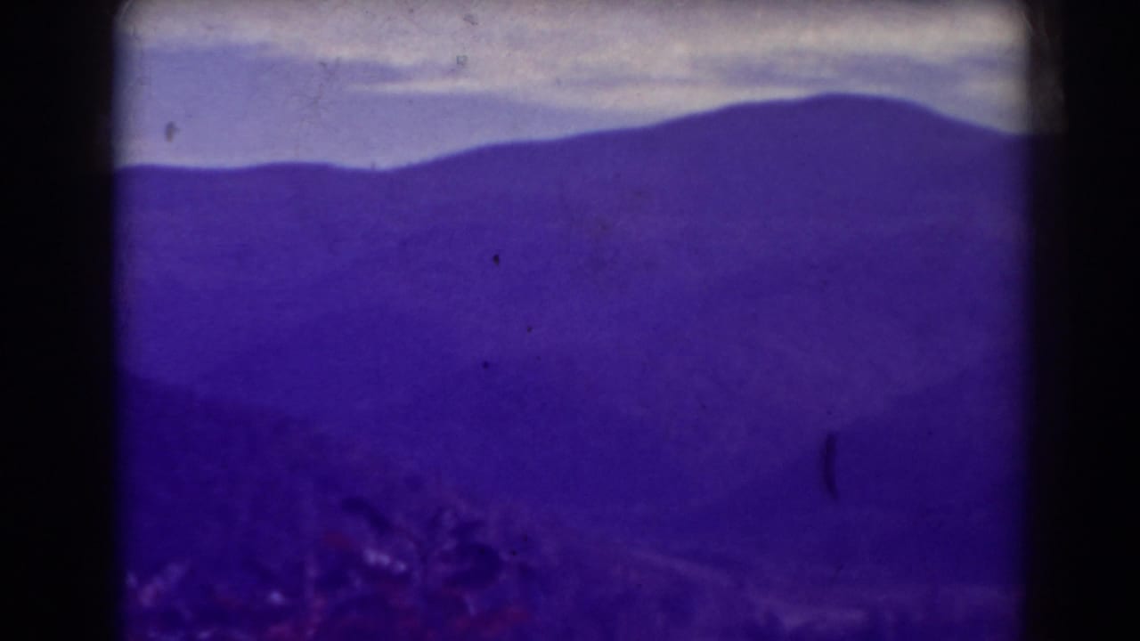 Layered mountain ridges under a pale sky with dark 8mm frame edges.