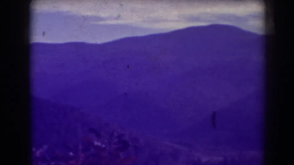 1938 Blackwater Falls home-movie frame showing distant West Virginia mountain ridges beneath a pale clouded sky.