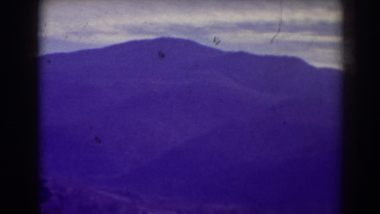 Distant mountain range and cloudy sky seen through a dark-edged film frame.