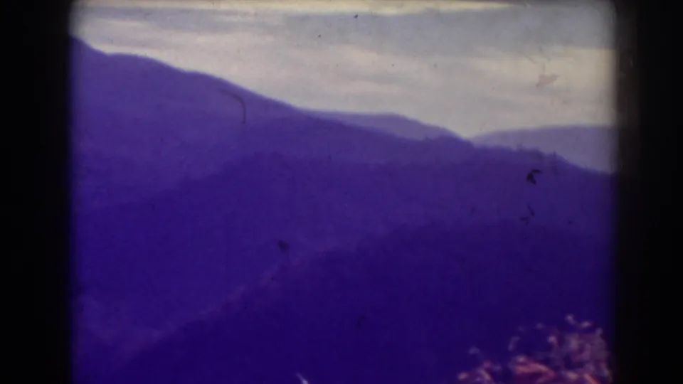Blackwater Falls 1938 home-movie frame with layered mountain ridges, pale sky, and visible 8mm film artifacts.