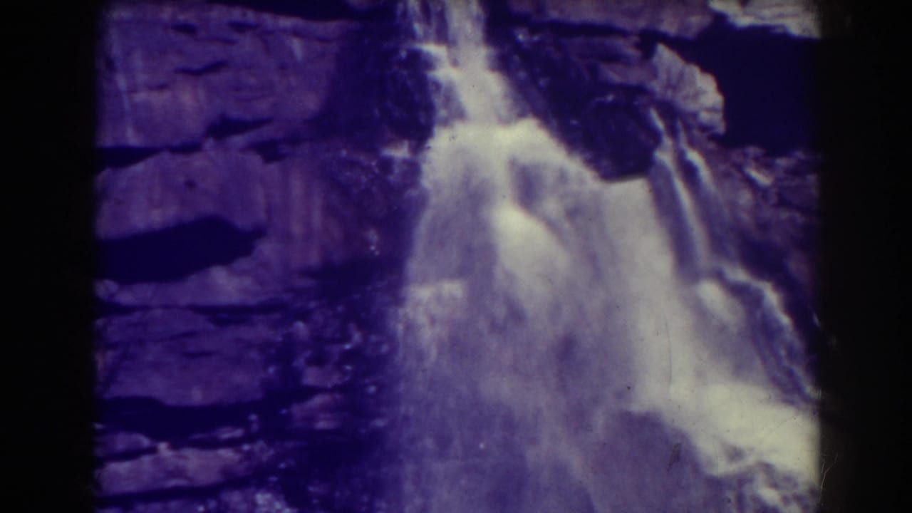 A steady 1938 view of Blackwater Falls shows white water spreading over dark layered stone in a grainy 8mm frame.