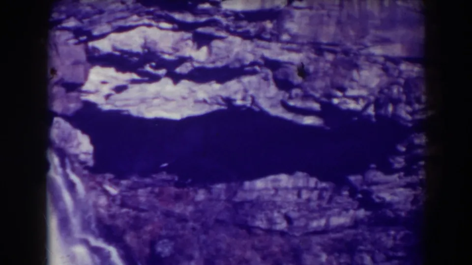 Blackwater Falls, West Virginia, viewed from above on 8mm film, with rock shelves, shadowed water, and purple film color.
