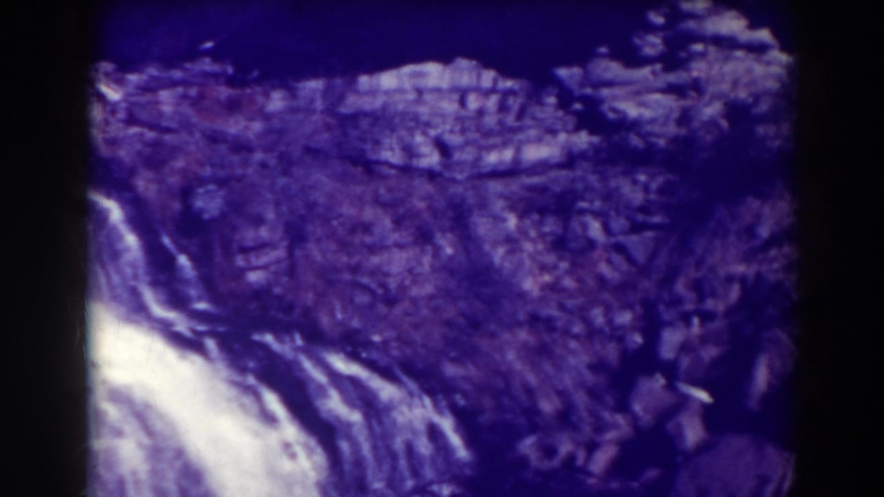 Close view of bright falling water against a dark rocky cliff.