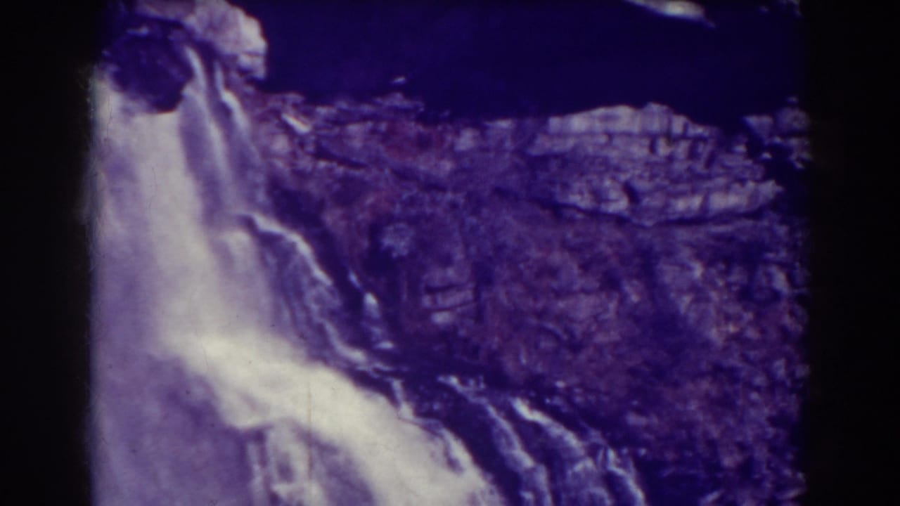 Waterfall cascading over dark rock ledges with a strong purple color cast.