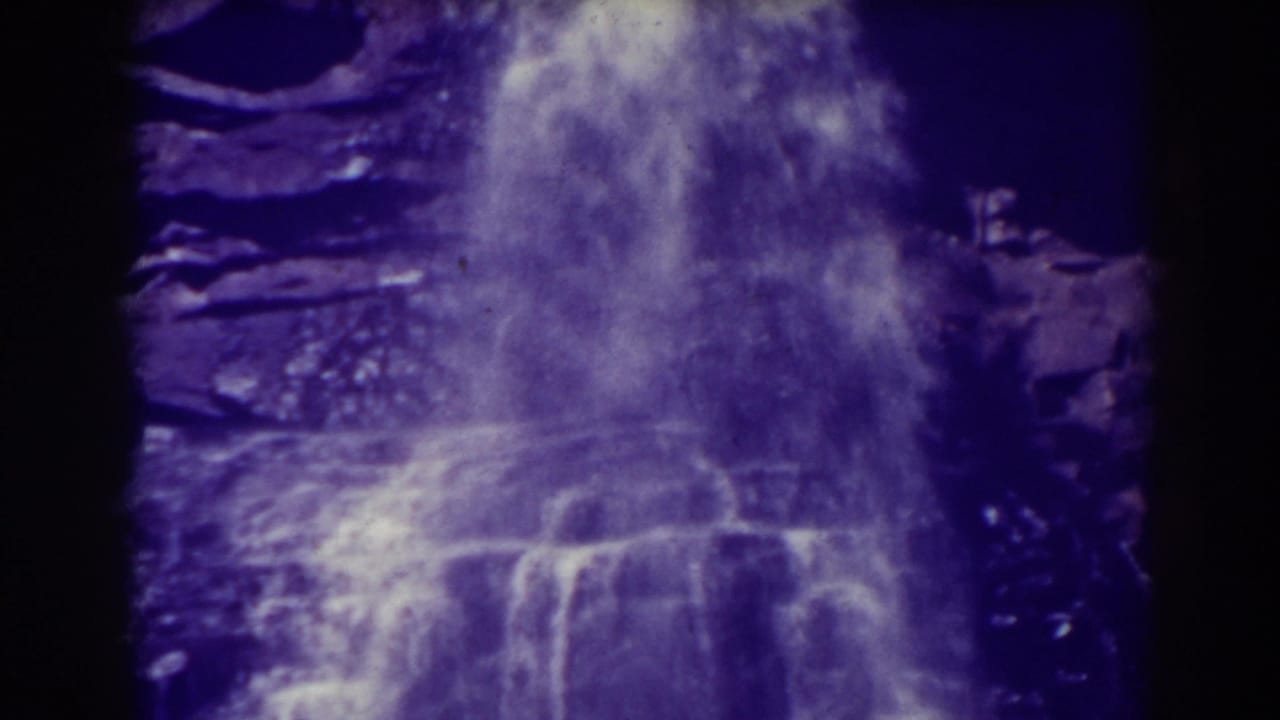Close view of water cascading over a dark rocky cliff.
