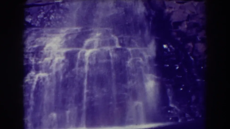 The lower Blackwater Falls view shows bright falling water, mist near the base, and dark surrounding rock in grainy color film.
