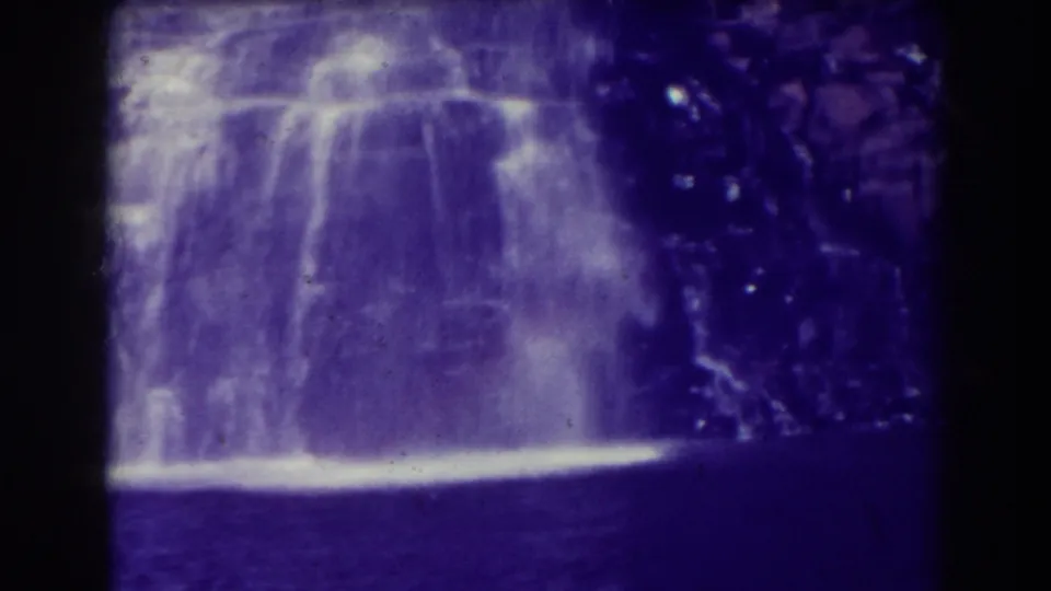 Blackwater Falls, West Virginia, seen in 1938 8mm footage as water pours over rocks into a dark pool with visible film grain and purple cast.