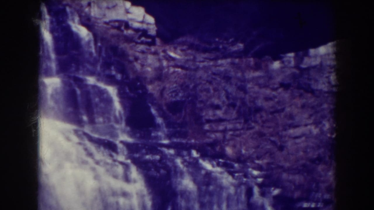 1938 8mm frame of Blackwater Falls showing white cascades crossing a rugged rock face with deep shadow at the lower edge.