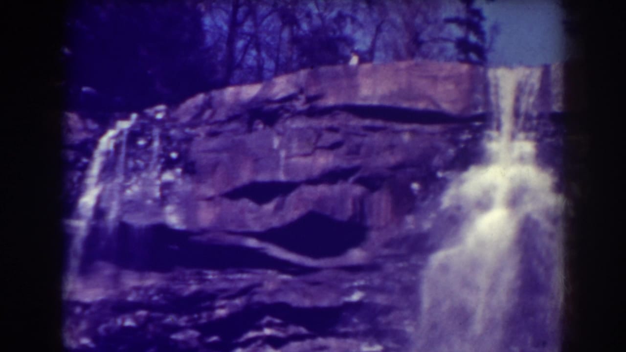Blackwater Falls appears in a steady 1938 home-movie frame, with white water crossing a dark rocky cliff face.