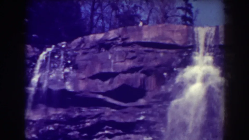 Blackwater Falls appears in a steady 1938 home-movie frame, with white water crossing a dark rocky cliff face.