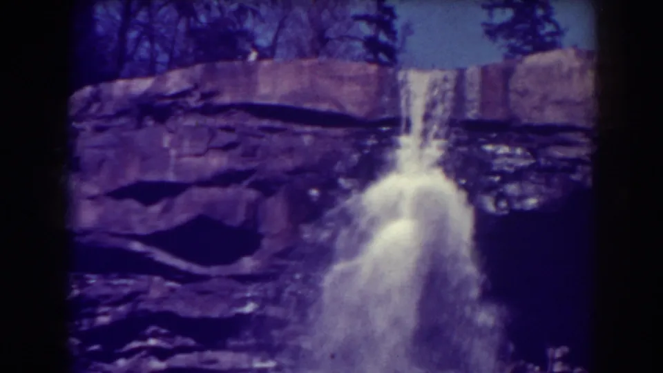 A closer 8mm frame of Blackwater Falls shows bright water plunging past purple-tinted rock strata.