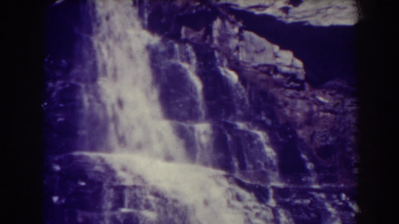Blackwater Falls in West Virginia, shown as a bright cascade over rugged stone in purple-tinted 8mm footage from 1938.